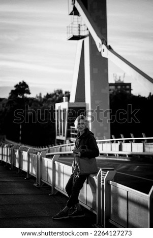 A woman tourist stands on the metal bridge, Portugal. Black and white photo.