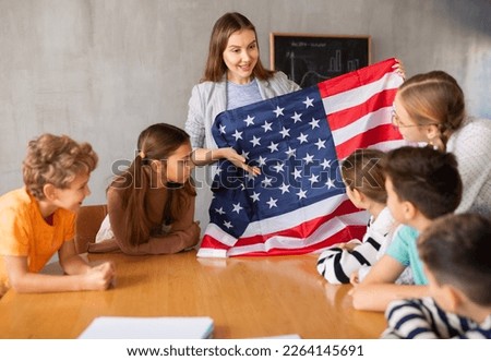 Geography lesson in school class - teacher talks about United States of America, holding a flag in his hands Royalty-Free Stock Photo #2264145691