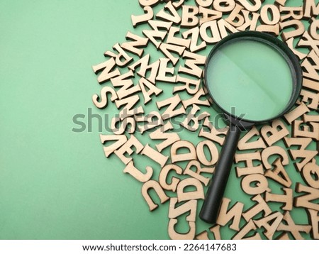 Wooden word and magnifying glass on a green background. Business concept. Royalty-Free Stock Photo #2264147683
