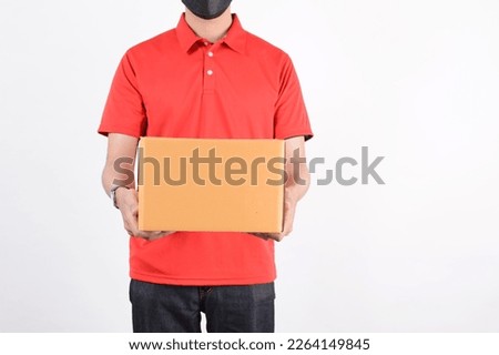 Delivery man employee in red cap blank t-shirt uniform face mask cardboard box isolated on white background. Service quarantine pandemic in front with copy space coronavirus virus 2019 concept.
