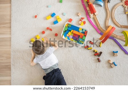 Preschool baby boy playing wooden Montessori materials rainbow arch railways at childish room. Playthings storage cupboard arrangement organizing. Male kid with natural eco friendly toys at home.  Royalty-Free Stock Photo #2264153749