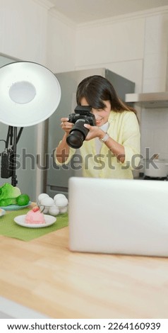 asian female photographer is using digital camera to take pictures in kitchen 