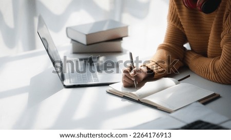 Asian teenage woman sitting in white office with laptop, she is a student studying online with laptop at home, university student studying online, online web education concept. Royalty-Free Stock Photo #2264176913