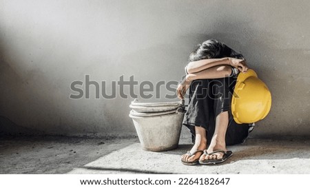 Exhausted little girl sitting on floor concrete wall background. child labor and exploitation Royalty-Free Stock Photo #2264182647