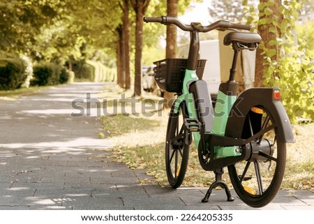 Bike or Electric Bicycle for Rental Service in Green City. Urban Electro bike charging battery in the Park. To rent