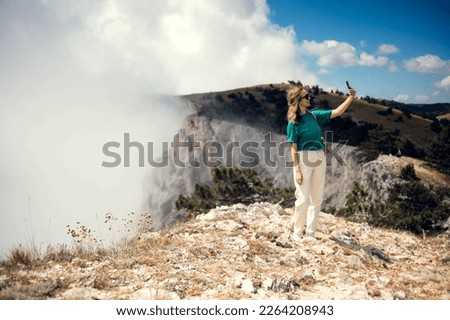 Young woman traveler taking photo with smart phone at sea of mist and sunrise over the mountain