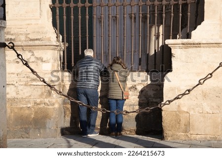 Older couple looking through railings inside gothic style cathedral in seville. Spain. Tourism and travel concept. Photo taken from be