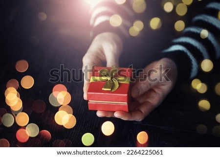 Top view of male and female hands holding gift box with golden ribbon on pink background Flat lay. Present for birthday, valentine day, Christmas, New Year. Congratulations background copy space.