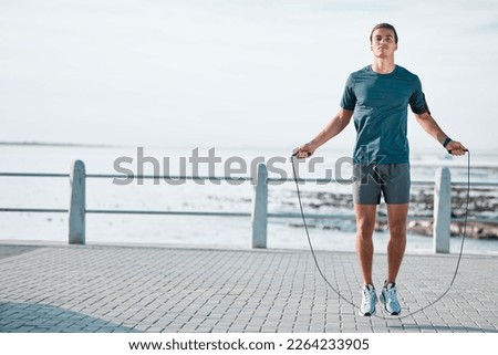 Skipping rope, mockup and man training by the beach for his outdoor morning exercise, workout and fitness routine. Athlete, cardio and male jump by the ocean or sea for wellness lifestyle Royalty-Free Stock Photo #2264233905