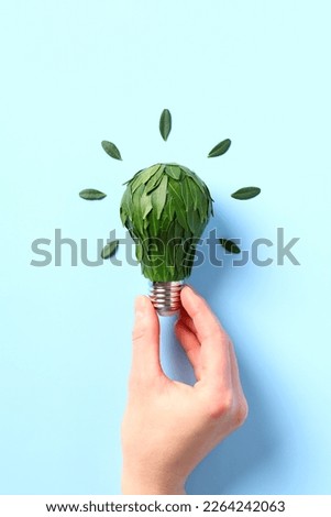 Eco-friendly lightbulb with green leaves in female hand. Energy saving, ecology, Save the Planet, Earth hour concept. Royalty-Free Stock Photo #2264242063