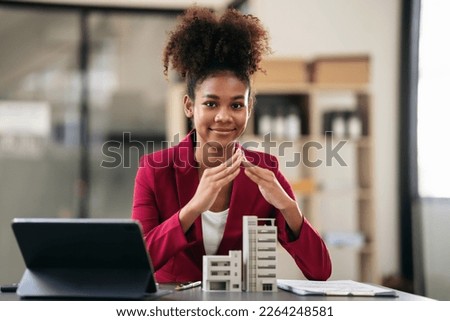 African american businesswoman in suit using hands to protecting of condominium model and working on tablet with contract document about renting or buying and insurance housing in workspace modern. Royalty-Free Stock Photo #2264248581