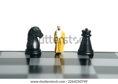 Miniature people toy figure photography. Defense attack strategy concept. A Sultan standing above chess board in between horse and castle knight pawn. Isolated on white background. Image photo