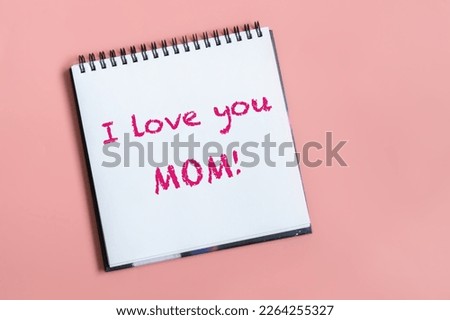 Text words I love you mom on sheet of paper. Happy mothers day concept. Pastel pink background. Royalty-Free Stock Photo #2264255327