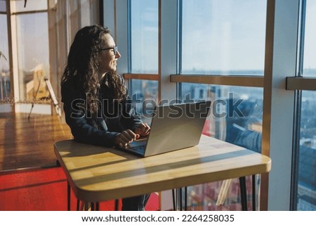 Top view of experienced woman in glasses working with laptop in coworking space, young freelancer working remotely with ideas for blog website