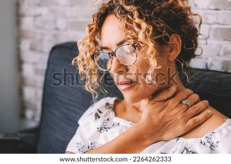 Sick middle age adult young women touching the neck have shoulder and neck pain.Healthcare and medicine concept. Female people suffering shoulder disease at home sitting on the sofa Royalty-Free Stock Photo #2264262333