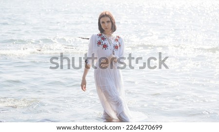 Young woman in white dress enjoys sea.