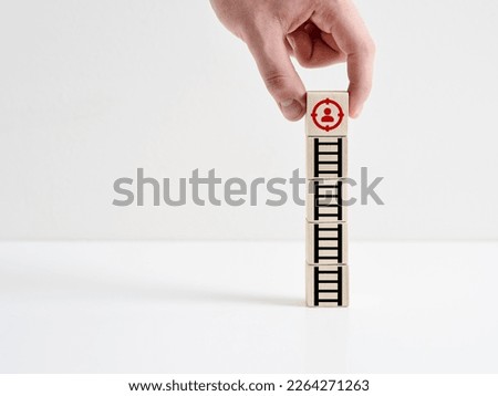 Target customer. Targeted audience marketing and customer centric strategies. Reaching the target market. Hand places a wooden cube with customer icon on the cubes with ladder icon.

 Royalty-Free Stock Photo #2264271263