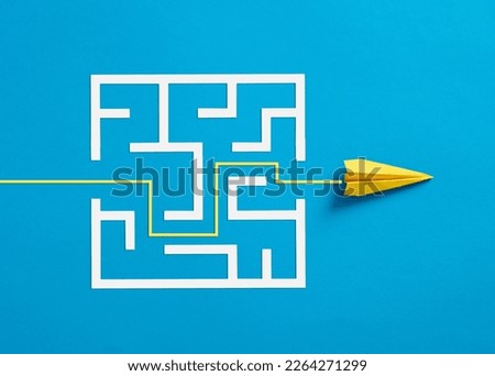 Overcoming the barriers. Conquering the obstacles. Way to success and business solutions. Exit strategy. Paper plane breaking through the maze on blue background. Royalty-Free Stock Photo #2264271299