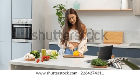 An attractive blogger cuts a vegetable salad while broadcasting the process live. Healthy eating, vegetarianism. Royalty-Free Stock Photo #2264274311