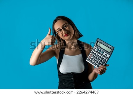 Photo of the CEO of a young brunette lady holding a calculator shouting wearing glasses isolated on a blue background. business. Business lady. strict woman portrait of a woman