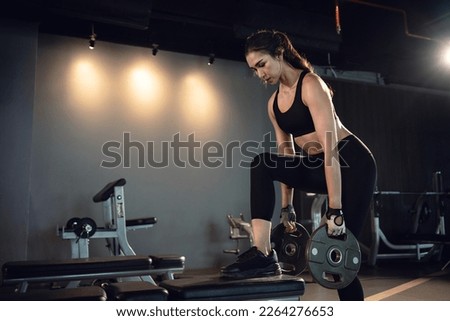 Sporty woman exercising with weight plate in the gym. Royalty-Free Stock Photo #2264276653
