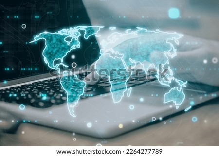 Close up of laptop on desktop with glowing map hologram on blurry tech background. Global world and perspective concept. Double exposure