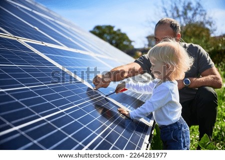 Man showing his small child the solar panels during sunny day. Father presenting to son modern energy resource. Little steps to alternative energy. Royalty-Free Stock Photo #2264281977