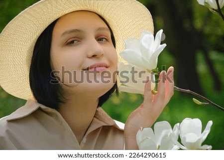 beautiful young woman in sunhat near magnoia blossoms close up portrait