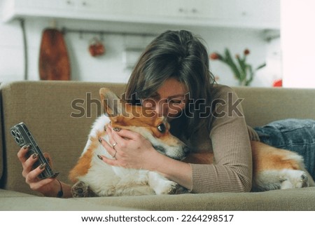 Owner female woman young girl playing kissing with her dog welsh corgi pet . High quality photo