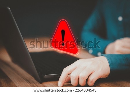 Adult man using a computer laptop with triangle caution warning sign for notification error. Concept technology of computer virus detected, personal data protection, network security and maintenance.