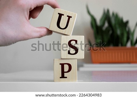 Hand holding wood cube block with 'USP' text. USP - short for Unique Selling Point