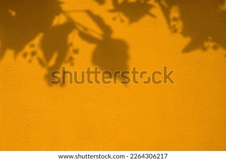 Abstract leaves shadows on saturated yellow concrete wall texture with roughness and irregularities. Abstract nature concept background. Copy space for text overlay poster mockup flat lay 