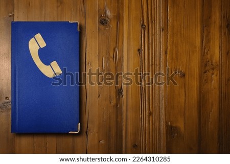 Close-up on a blue phone book on a wooden desk.