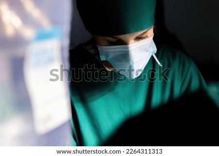 female caucasian surgeon working operating room. female nurse wear mask performing emergency operation. professional surgical woman wearing mask doing surgery to save patient life in operating room.