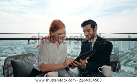Young businessman and woman discuss and sign business deals on tablet at office building