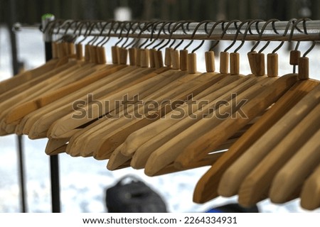 Many wooden hangers on a rod. Store concept, sale, design, empty hangers. Black friday. Wooden coat hanger clothes. Fashionable different types of hanger. Wood Hangers coat. Blurred focus.