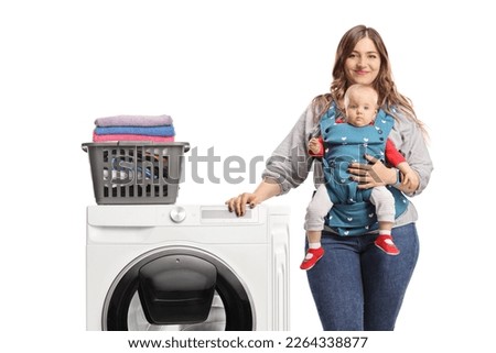 Mother with a baby leaning on a washing machine with a laundry basket isolated on white background Royalty-Free Stock Photo #2264338877