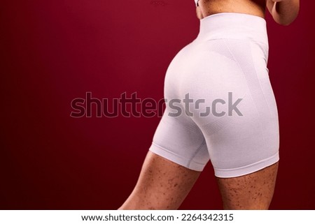 A fitness woman with spotted skin showing her glute gains, dressed in new sports shorts. Royalty-Free Stock Photo #2264342315