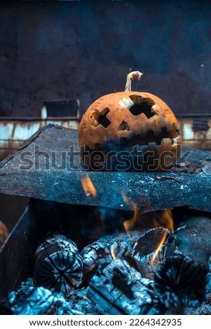 orange halloween pumpkin in ashes from the fire in the yard