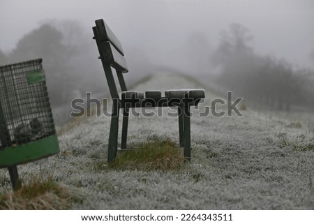 Parkbench and a dustbin on a dike as a closeup Royalty-Free Stock Photo #2264343511