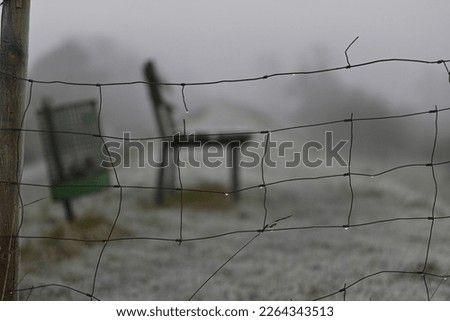 Parkbench and a dustbin behind a sheepfence on a dike Royalty-Free Stock Photo #2264343513