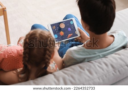 Little boy and girl watching cartoons on tablet computer at home, closeup