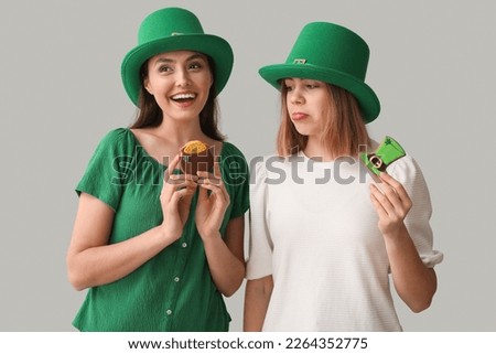 Young women with cookies on light background. St. Patrick's Day celebration