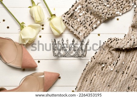 Beautiful tiara, dress, heels and roses on white wooden background. Prom concept Royalty-Free Stock Photo #2264353195