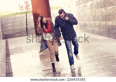 A picture of a young couple running in the rain in the city