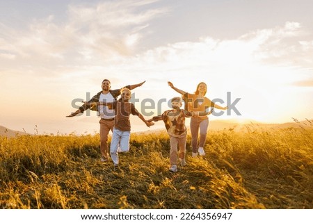 Happy family: mother, father, children son and  daughter running back on nature  on sunset