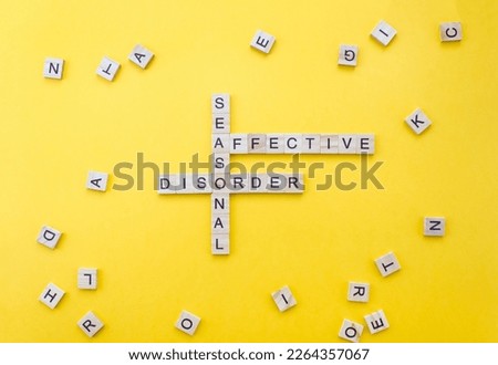 Words Seasonal Affective Disorder on wooden blocks with letters on a yellow background. Minimal SAD concept. Selective focus. Royalty-Free Stock Photo #2264357067