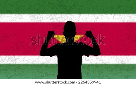 Young man in front of the Suriname flag, celebrating winning, fists up of happy man, happiness or joy concept, Suriname victory or championship idea, the silhouette of the screaming man
