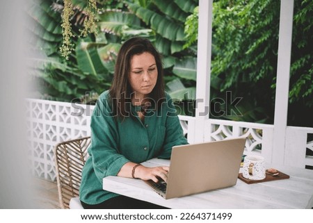 Skilled Caucasian woman searching media application for installing on modern laptop computer, millennial female blogger creating web content on portable netbook connecting to 4g wireless outdoors