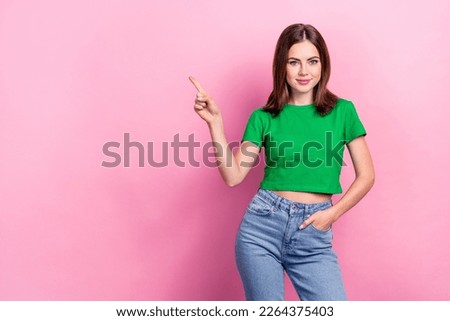 Photo of cheerful adorable girl green t-shirt indicating empty space arm in pocket demonstrate offer isolated on pink color background